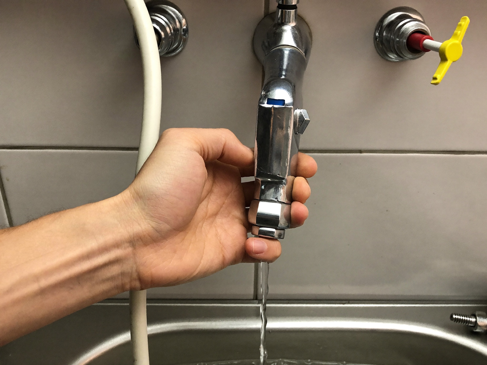 A plumber shutting off a water valve under a sink during an emergency