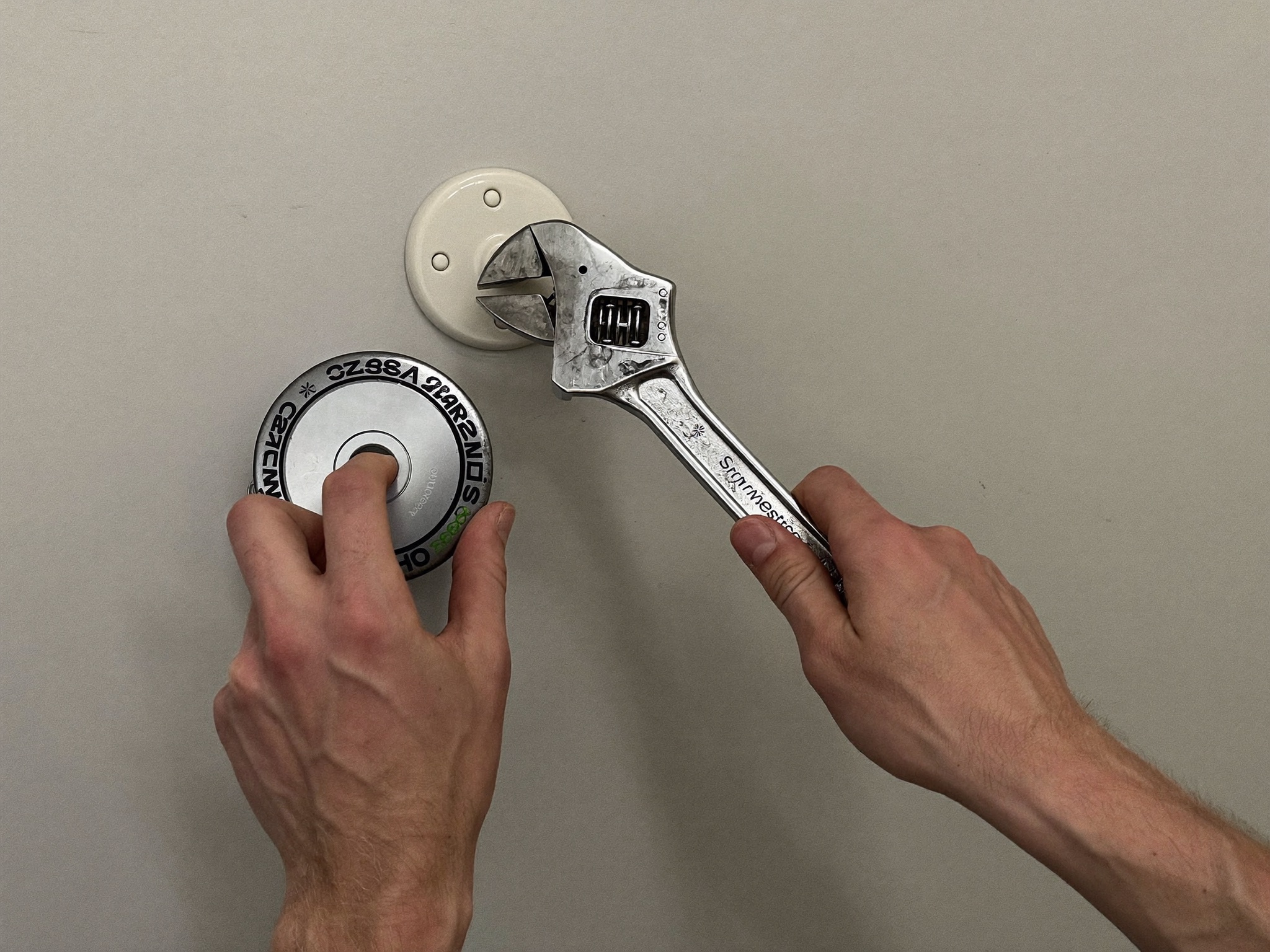 A plumber's hands using a wrench on a shutoff valve